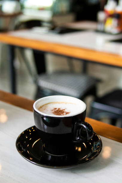 istock black coffee cup and hot cappuccino coffee on white wooden table. blur background 1134608242