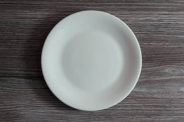 istock An empty white ceramic plate on grey wooden background 1134610720
