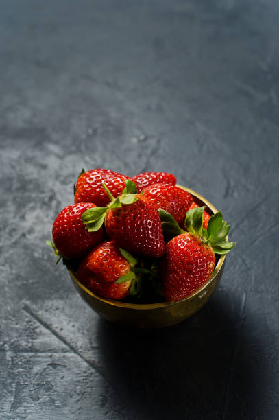 istock Ripe strawberries in a Golden bowl. Black background, side view, space for text. 1134614782