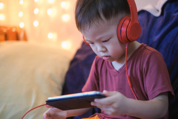 carino piccolo asiatico 2 -3 anni bambino bambino ascolto musica con cuffie da smartphone - toddler music asian ethnicity child foto e immagini stock