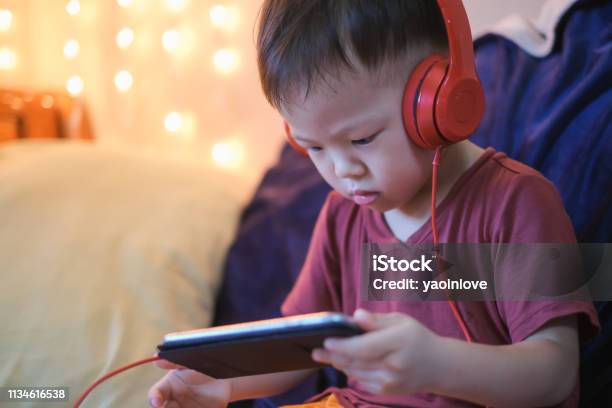 Carino Piccolo Asiatico 2 3 Anni Bambino Bambino Ascolto Musica Con Cuffie Da Smartphone - Fotografie stock e altre immagini di Bambino