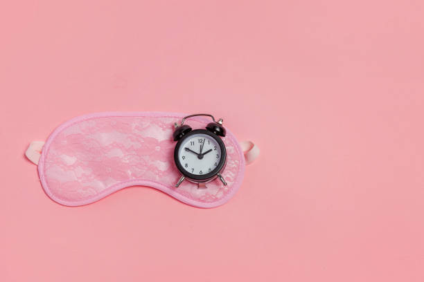 istock Sleeping mask and alarm clock on pink background 1134623853