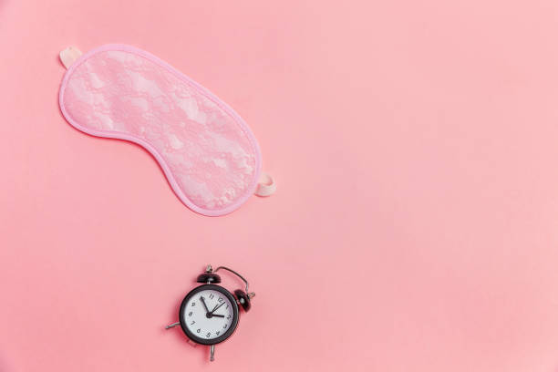 istock Sleeping mask and alarm clock on pink background 1134625641
