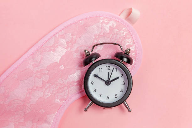 istock Sleeping mask and alarm clock on pink background 1134626951