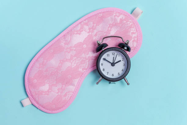istock Sleeping mask and alarm clock on blue background 1134627066