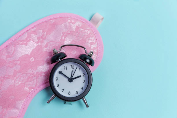 istock Sleeping mask and alarm clock on blue background 1134627684