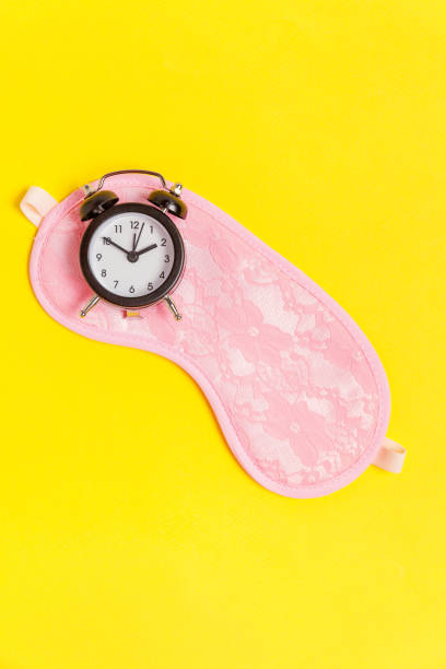 istock Sleeping mask and alarm clock on yellow background 1134628204