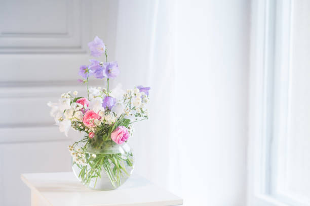 istock Bedside table, vase with rose and lilac flowers.  White background. Copy space 1134639365