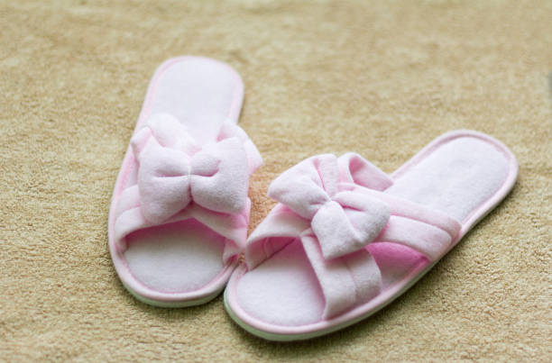 istock pink soft Slippers with a bow stand on a beige rug 1134649330