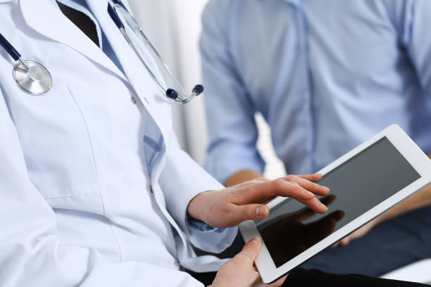 istock Female doctor using touchpad or tablet computer while consulting man patient in hospital. Medicine and healthcare concept 1134655314