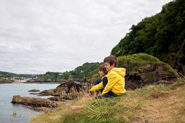 아이 들, 절벽에 있는 오션 쇼 어의 조용한 흐린 날을 즐기는 바위 해변 - cliff at the edge of grass sea 뉴스 사진 이미지