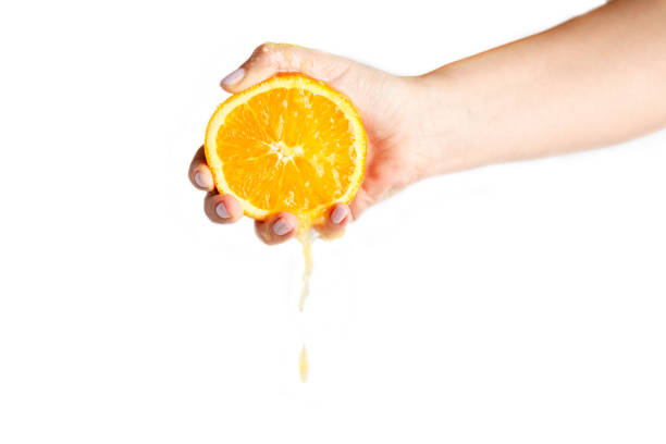 istock female hand crushes orange on white background 1134658906