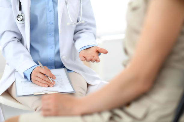istock Doctor and patient talking. Physician at work in hospital while writing up medication history records form on clipboard near sitting woman. Healthcare and medicine concepts 1134660201