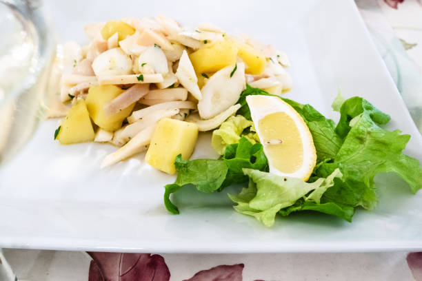 Italian cuisine - insalata di Polpo (salad from potato, octopus, squid and cuttlefish) close up on white plate in local restaurant in Lombardy