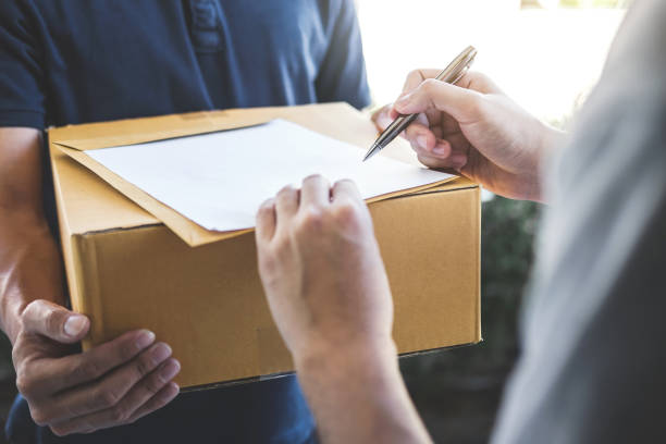 istock Midsection Of Man Signing Document While Receiving Package From Delivery Person 1134673327