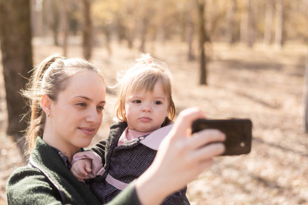 istock Young mother is taking a selfie with her daughter while holding her in the park 1134679480