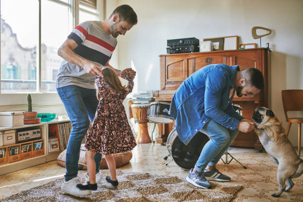 couple gai dansant avec la fille et le carlin à la maison - dog family indoors child photos et images de collection