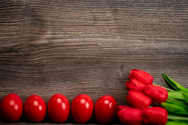 Easter eggs and tulips on wooden background.