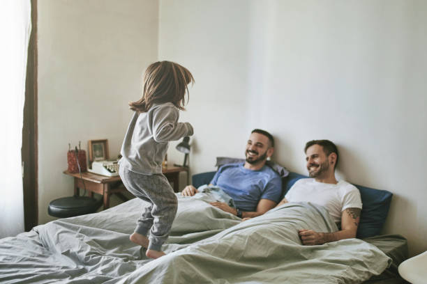 istock Smiling parents looking at daughter jumping on bed 1134695099