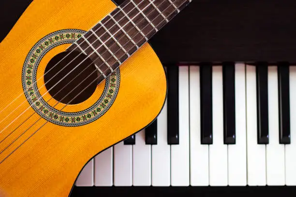 Photo of Guitar on piano. Classical music instrument. Top view with copy space.