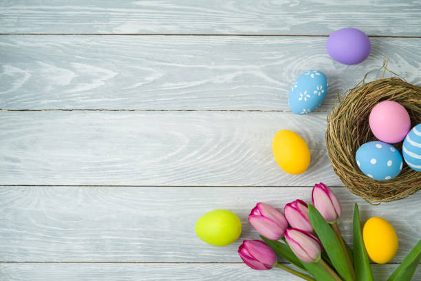 sfondo delle vacanze di pasqua con uova di pasqua in nido di uccelli e fiori di tulipano su tavolo di legno - wood eggs easter easter egg foto e immagini stock