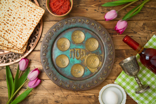 festa ebraica pasqua sfondo con matzo, piatto di seder, vino e fiori di tulipano su tavolo di legno. - matzo passover seder judaism foto e immagini stock