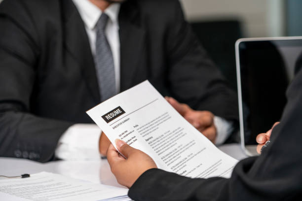 gerente de departamento de recursos humanos lê cv currículo documento de um candidato empregado na sala de entrevista. aplicação de emprego, recrutamento e contratação de trabalho conceito. - humanism - fotografias e filmes do acervo