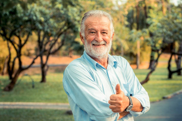 公園に立っている幸せなシニア男性の肖像。長老の健康と退職の概念. - casual cheerful looking at camera outdoors ストックフォトと画像