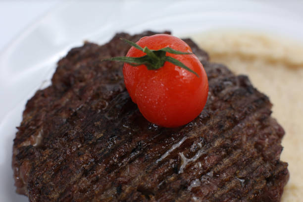 fried meat cutlet on a plate, with celery puree, garnished with tomato cherry and sour apples, isolated