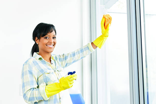 istock A woman wearing gloves and smiling while cleaning a window 113470876