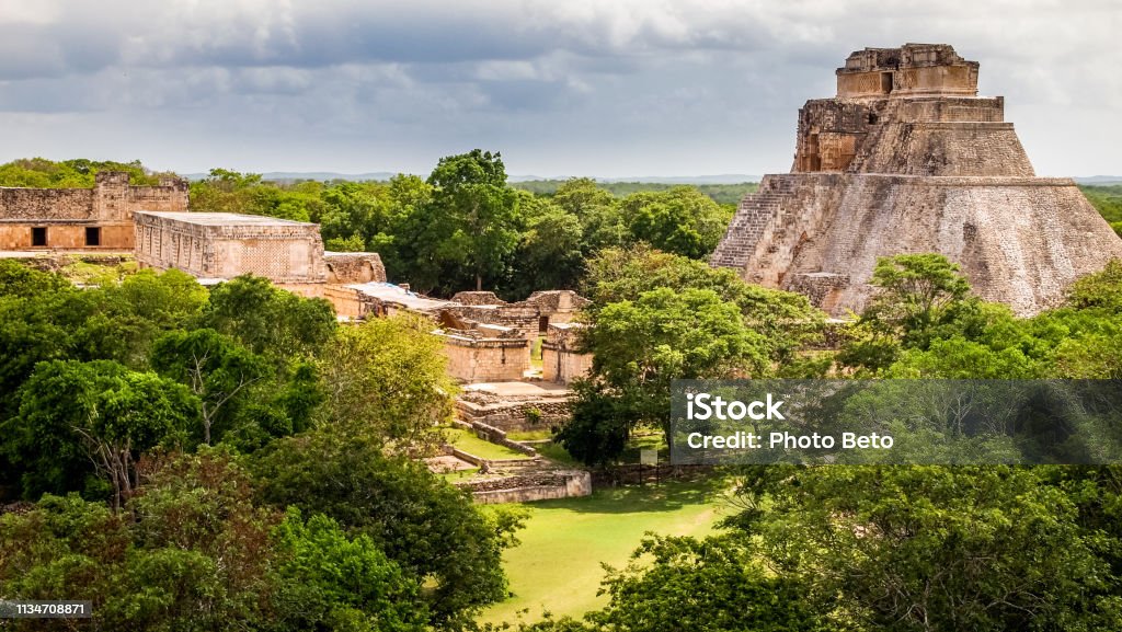 A beautiful view of the Pyramid of the Magician in the Mayan archaeological site of Uxmal in the Yucatan in Mexico Uxmal, Mexico, May 30 - Through the ancient Mayan city of Uxmal, 80 km from Merida, capital of the Mexican state of Yucatan. Proclaimed a World Heritage Site in 1996, Uxmal was founded in the 6th century AD by the Puuc civilization and became one of the major centers of worship in the region. Immersed in the Yucatan rain forest and symbol of Mayan culture, Uxmal was discovered in 1838 by the French archaeologist Jean Frederic Waldeck. In the picture a panoramic view of the Pyramid of the Fortune-teller and the Governor Palace. Mexico Stock Photo
