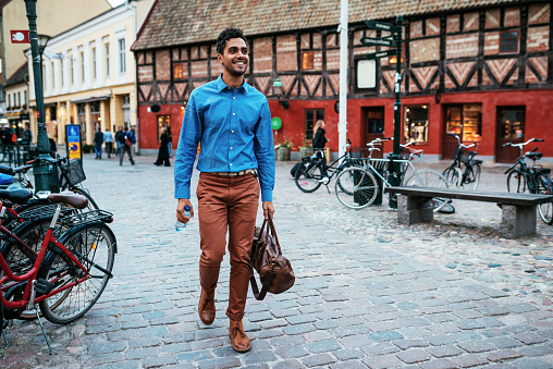 Portrait of Latin American young man in smart casual clothing, representing young businessman, entrepreneur or University student. Handsome Brazilian in blue shirt commuting to work, having coffee break or communicating with business partners.