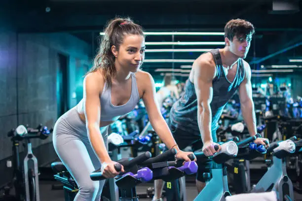 Photo of Attractive woman and handsome man doing exercising on cycling bikes