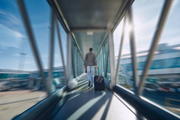 Man hurrying at airport Man hurrying at airport. Rear view of passenger with luggage walking to terminal. passenger boarding bridge stock pictures, royalty-free photos & images