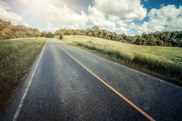 夏の日の青空に白い雲の下の緑の芝生フィールドで丘の上の高速道路の道路。道路の旅行の旅行の概念。 - landscape hill green grass ストックフォトと画像