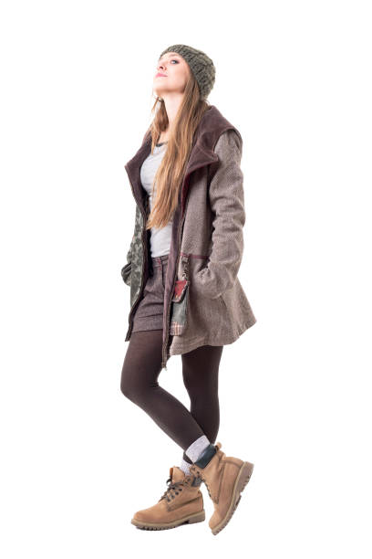 istock Stylish hipster girl in winter clothes wearing beanie and hooded coat looking at camera with attitude 1134731500