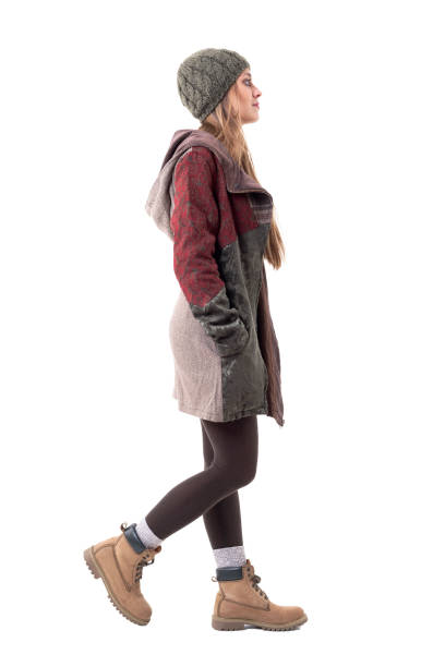 Profile view of beautiful cute young stylish hipster girl in winter clothes and cap walking.