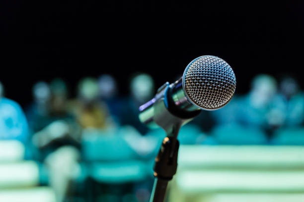 istock Wireless microphone on the stand. Blurred background. People in the audience. Show on stage in the theater or concert hall 1134731594
