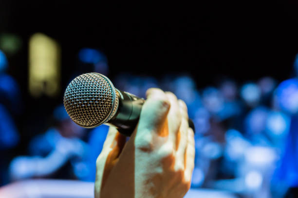 istock Wireless microphone in hand. Blurred image of people in the audience in the background 1134731696