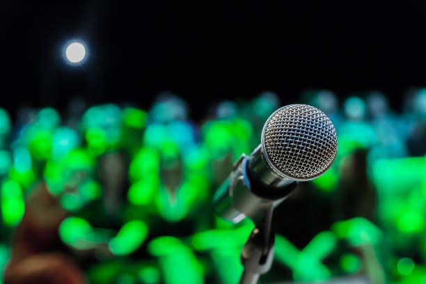 istock Wireless microphone on the stand. Blurred background. People in the audience. Show on stage in the theater or concert hall 1134731749