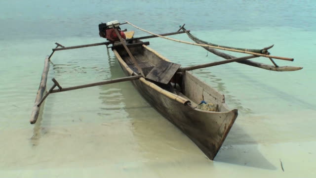 Old indonesian outrigger prahu on the shoreline