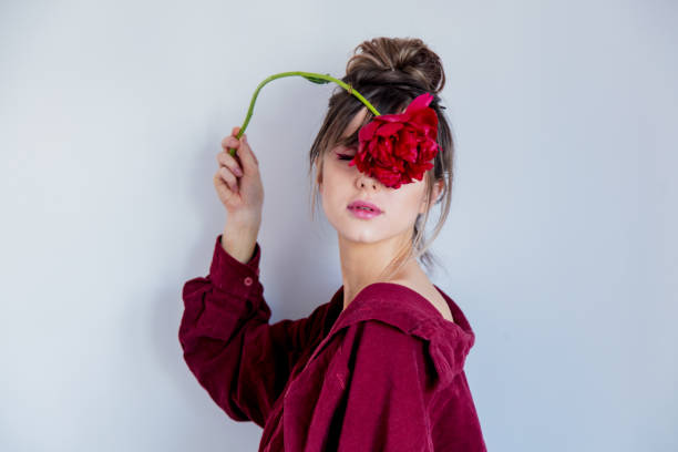 istock Female in red shirt holing red peony 1134734884