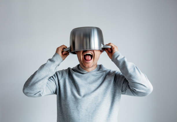 Crying man with pan on head o Crying man with pan on head on gray background stressed man funny stock pictures, royalty-free photos & images