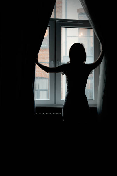 istock a young girl looks behind the curtains 1134734921