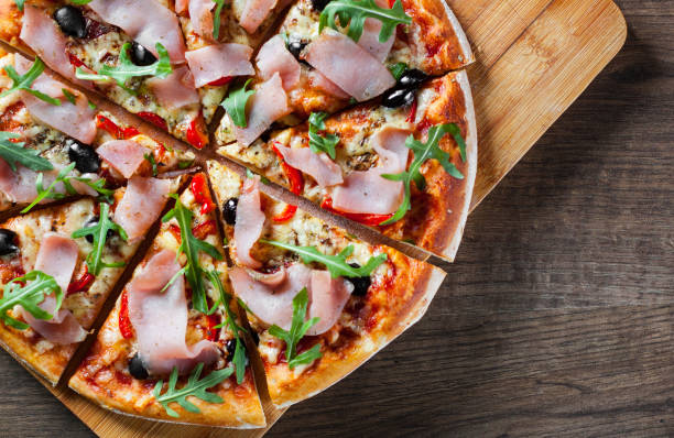 istock Pizza with Mozzarella cheese, ham, pepper, olive, meat, Tomato sauce, Spices and Fresh arugula. Italian pizza on wooden background 1134737878