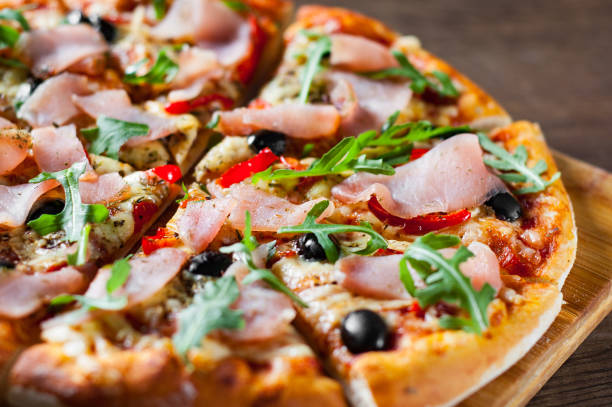 istock Pizza with Mozzarella cheese, ham, pepper, olive, meat, Tomato sauce, Spices and Fresh arugula. Italian pizza on wooden background 1134737888