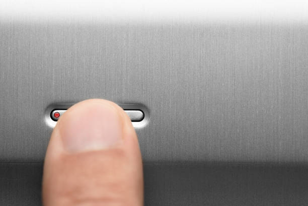 The power button on the aluminum panel. Male finger