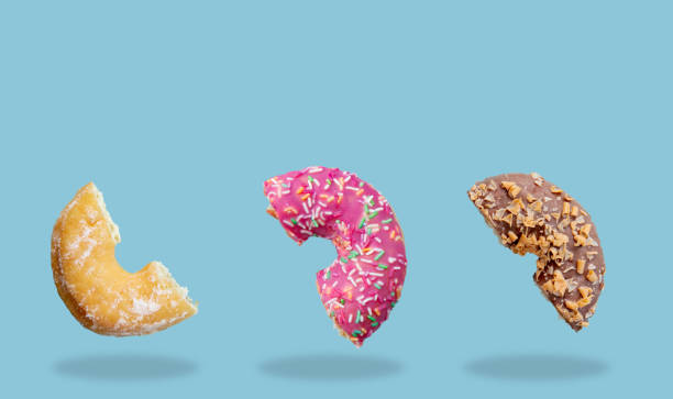 istock Sweet pink, chocolate and cream cut donuts fly in air 1134741382