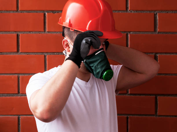 istock A man in a helmet and respirator performs painting work on a concrete ceiling, against a background of brickwork. The concept is workplace safety. DIY Do It Yourself. 1134747833