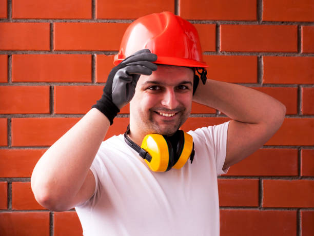 istock A man in a protective helmet and black gloves against a red brick wall, with noise-reducing headphones around his neck. DIY concept and safety. DIY Do It Yourself 1134747905